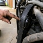 Worn accessory belt with cracked ribs on car engine in a home garage