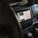Aftermarket car multimedia touchscreen unit mounted in vehicle dashboard showing navigation map