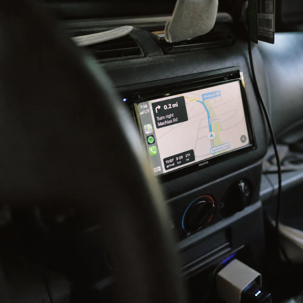 Aftermarket car multimedia touchscreen unit mounted in vehicle dashboard showing navigation map