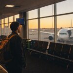 Empty international departure terminal at dawn with a widebody aircraft visible through large windows