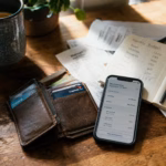 Open wallet and smartphone showing AI banking dashboard on a wooden desk with financial notes